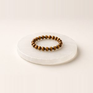 White selenite charging plate with a tiger eye bead bracelet resting on it