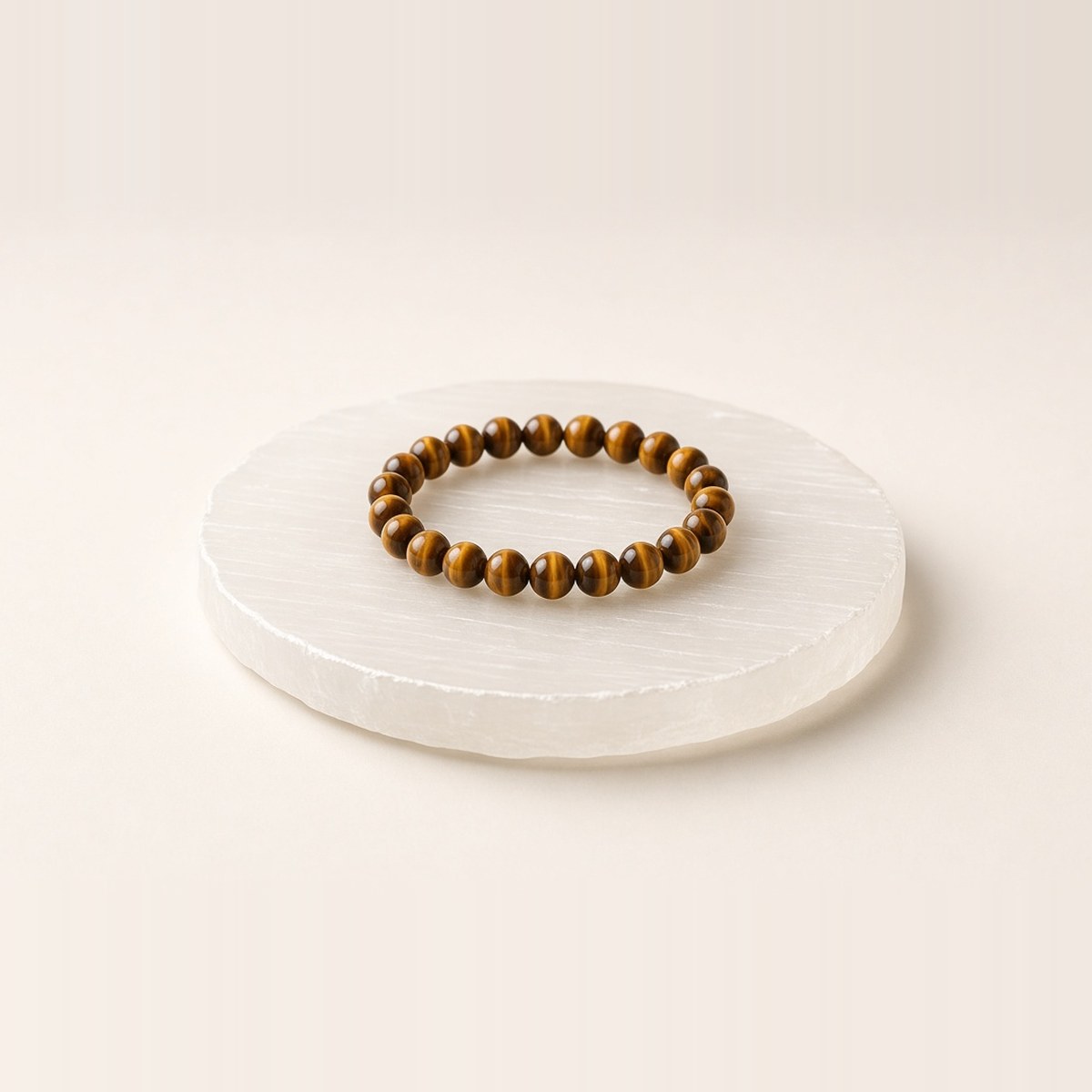 White selenite charging plate with a tiger eye bead bracelet resting on it