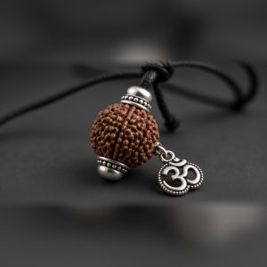 Close-up of the 5 mukhi rudraksha bead, silver-tone cap and Om charm of the Manka Om Rudraksha Pendant